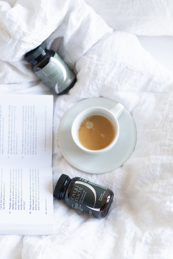 ovuu Nahrungsergänzungsmittel für Perimenopause auf einem Bett mit Kaffee und Buch